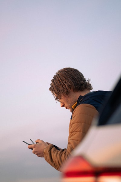 Dressed in a brown blue long sleeve shirt man holding a smartphone

